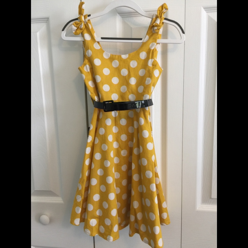 Yellow polkadot dress with patent leather belt .